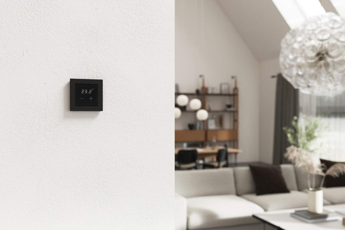 Raumtemperaturregler Cala T 101 KNX sec in schwarz an der Wand montiert vor modernem Wohnzimmer
