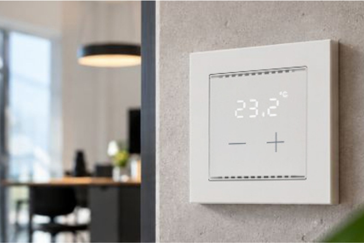 Wissenswertes zur KNX-Einzelraumregelung ➥ Raumtemperaturregler Cala T 101 KNX sec an Wand montiert vor modernem Wohnzimmer (KI-generiert)