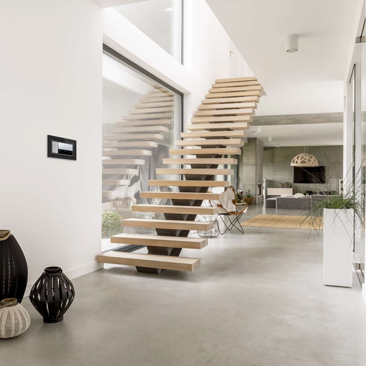 WS1000 Connect an der Wand neben einer freitragenden Holztreppe in einem hellen Wohnraum