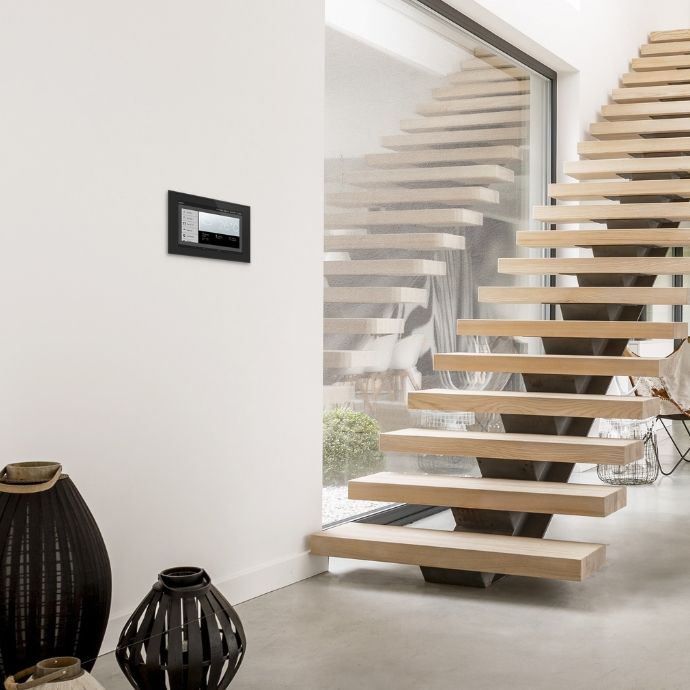 WS1000 Connect an der Wand neben einer freitragenden Holztreppe in einem hellen Wohnraum